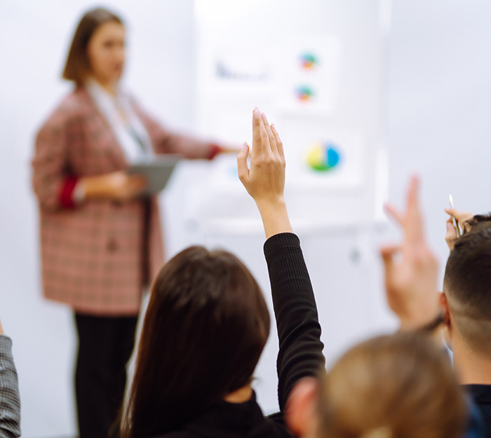 Two people raise their hands to be called on during a teaching seminar.