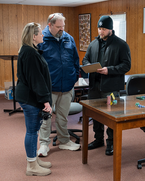 A group of police officers stand in a room and review crime scene information together.