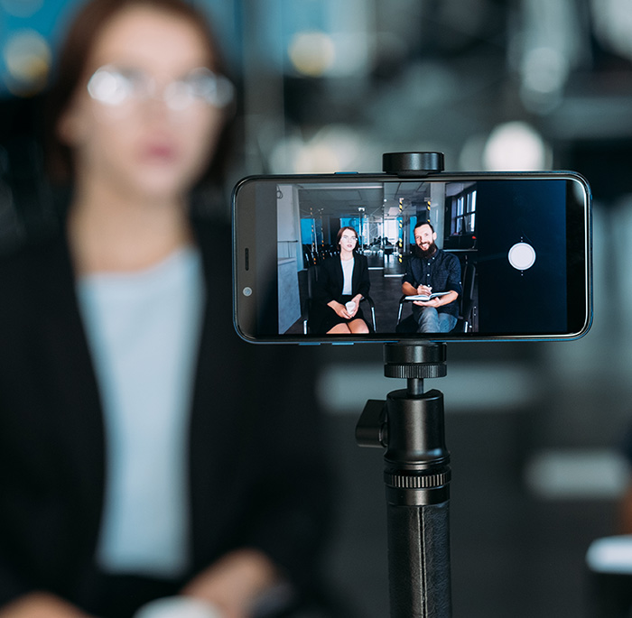 A smart phone records a video of two seated people talking.