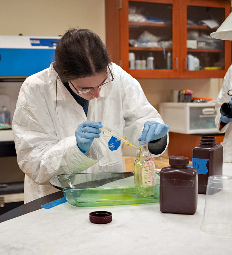 A collegiate NFA student conducts latent fingerprint analysis in a lab.
