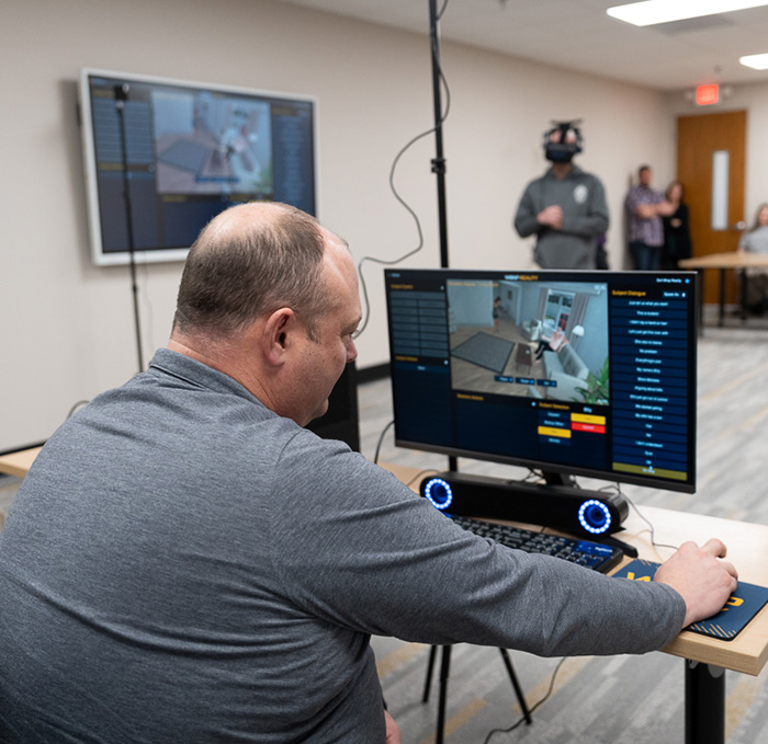 A police trainer runs a virtual simulation in a training room.