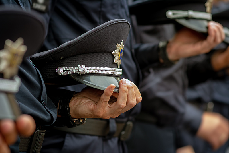 Close-up of a line of police officers holding their caps.