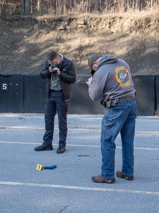 A two police officers practice forensic photography skills at a staged crime scene.