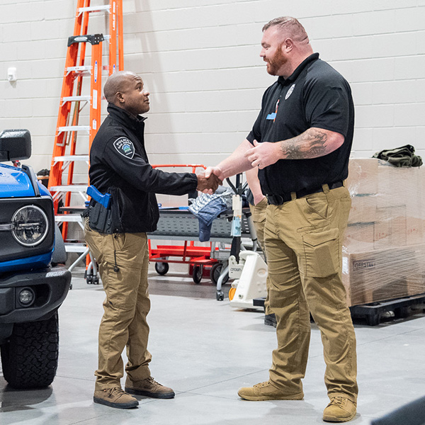 Two police officers shake hands during a simulation.
