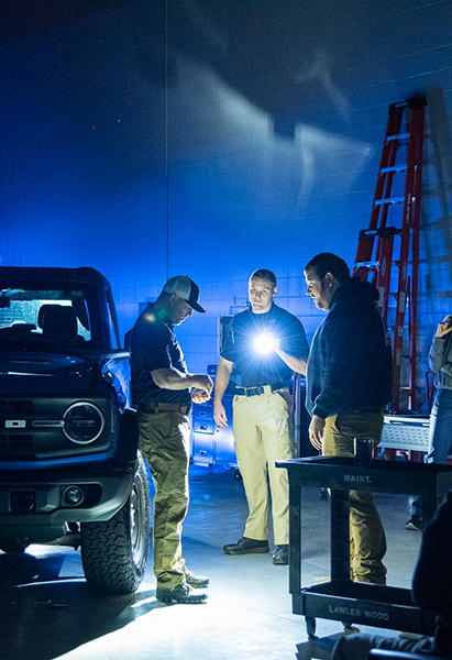 A group of police officers conduct a simulated nighttime training traffic stop.