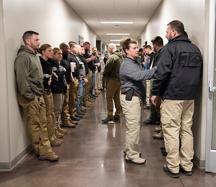 A group of officers lines up in a hallway and wait for instructions for their training activity.